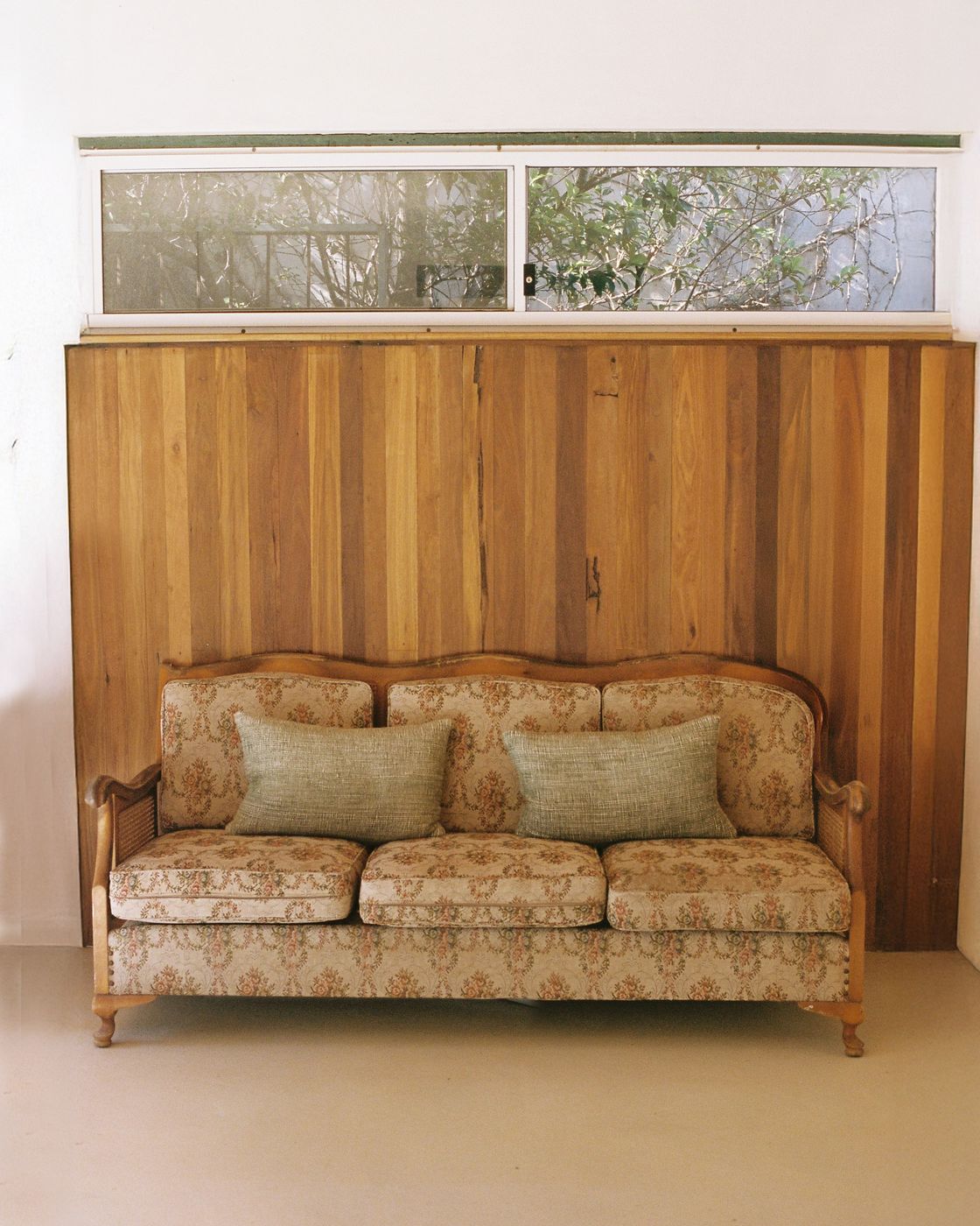 A cane sofa with floral upholstery under the hardwood feature wall