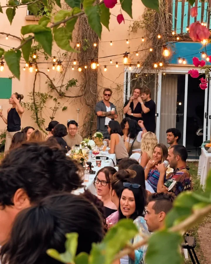 Guests at long tables beneath flowering vines and festoon lights in the Chalet courtyard