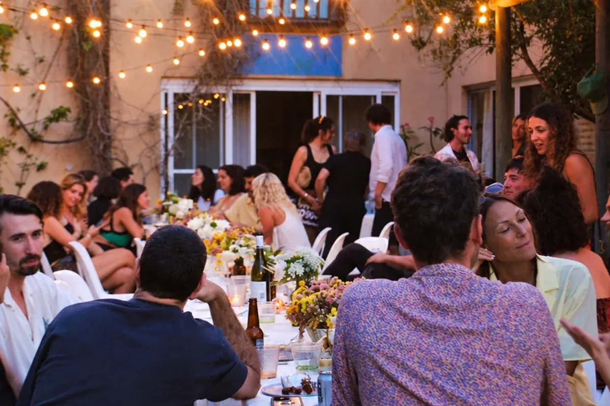Guests share an evening meal in the Chalet courtyard beneath warm festoon lights and the blue balcony